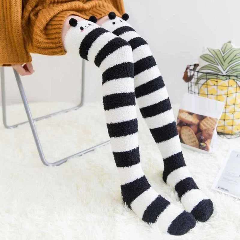 Black and white striped thigh high fuzzy socks worn on a fur rug