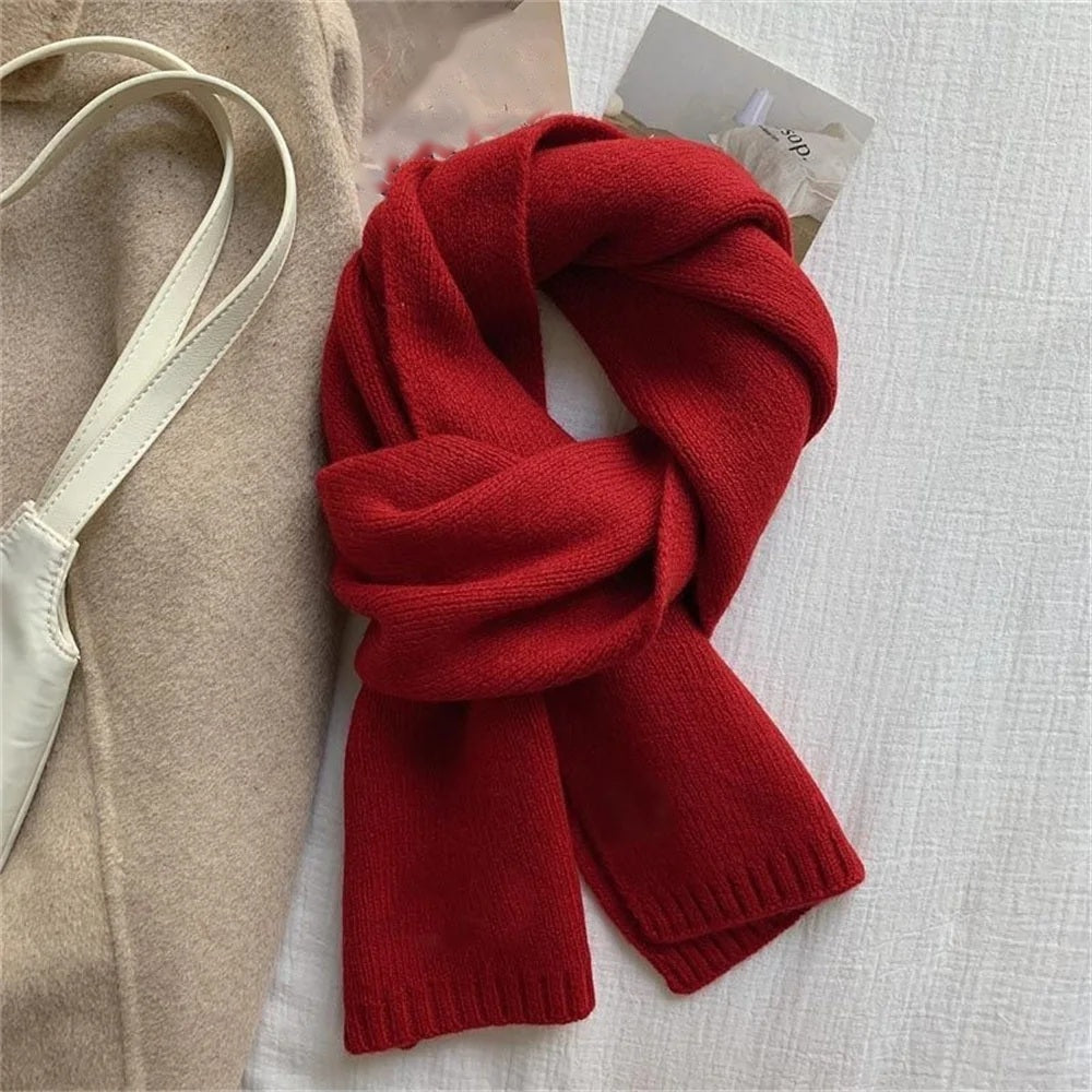 Red cashmere scarf knotted, flat lay on white bedding