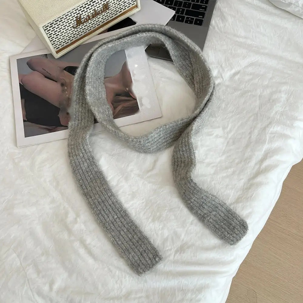 Grey cashmere scarf looped, flat lay on white bedding