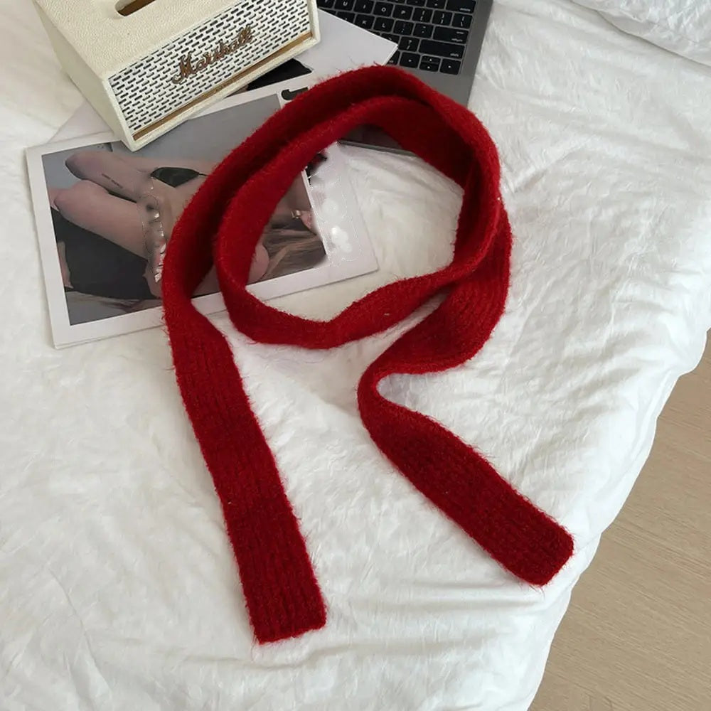 Deep red cashmere scarf looped, flat lay on white bedding