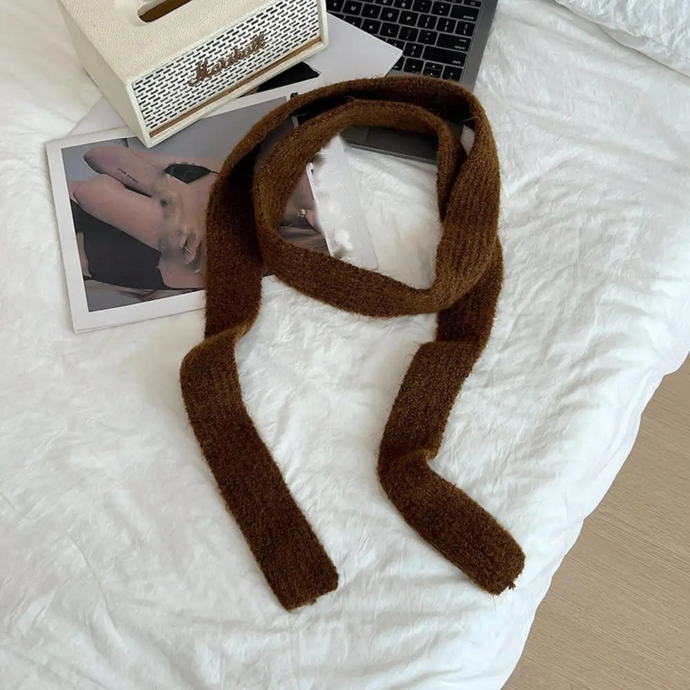 Rust brown cashmere scarf looped, flat lay on white bedding