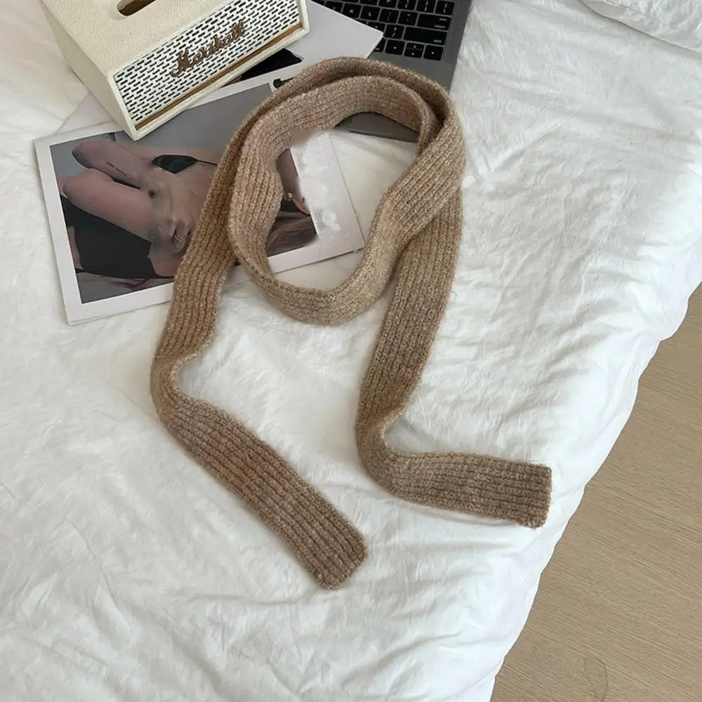 Tan cashmere scarf looped, flat lay on white bedding