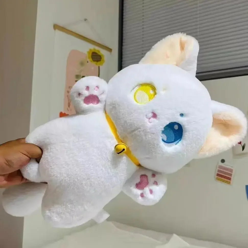White cat plush toy with yellow and blue eyes and a bell collar, held up in a bedroom