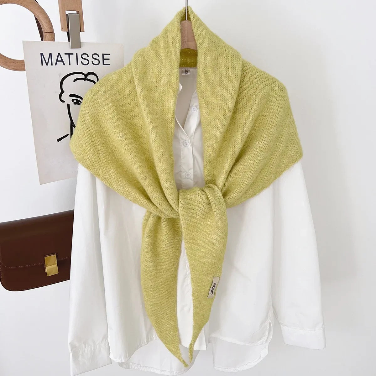 Yellow knit triangle wool scarf displayed on a hanger