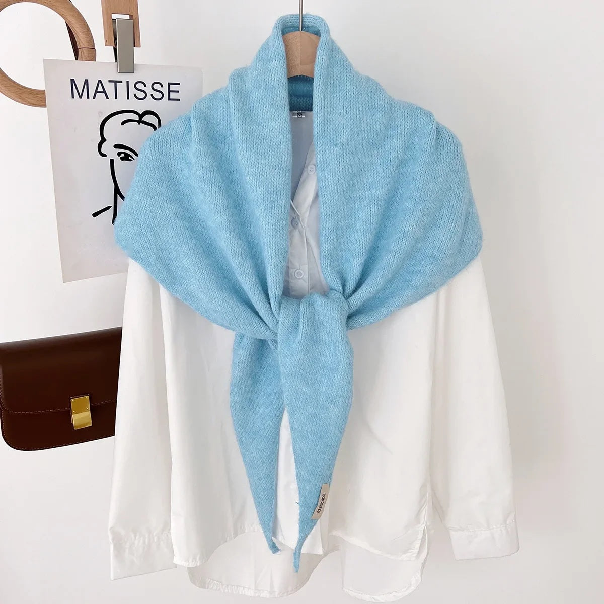 Light blue knit triangle wool scarf displayed on a hanger
