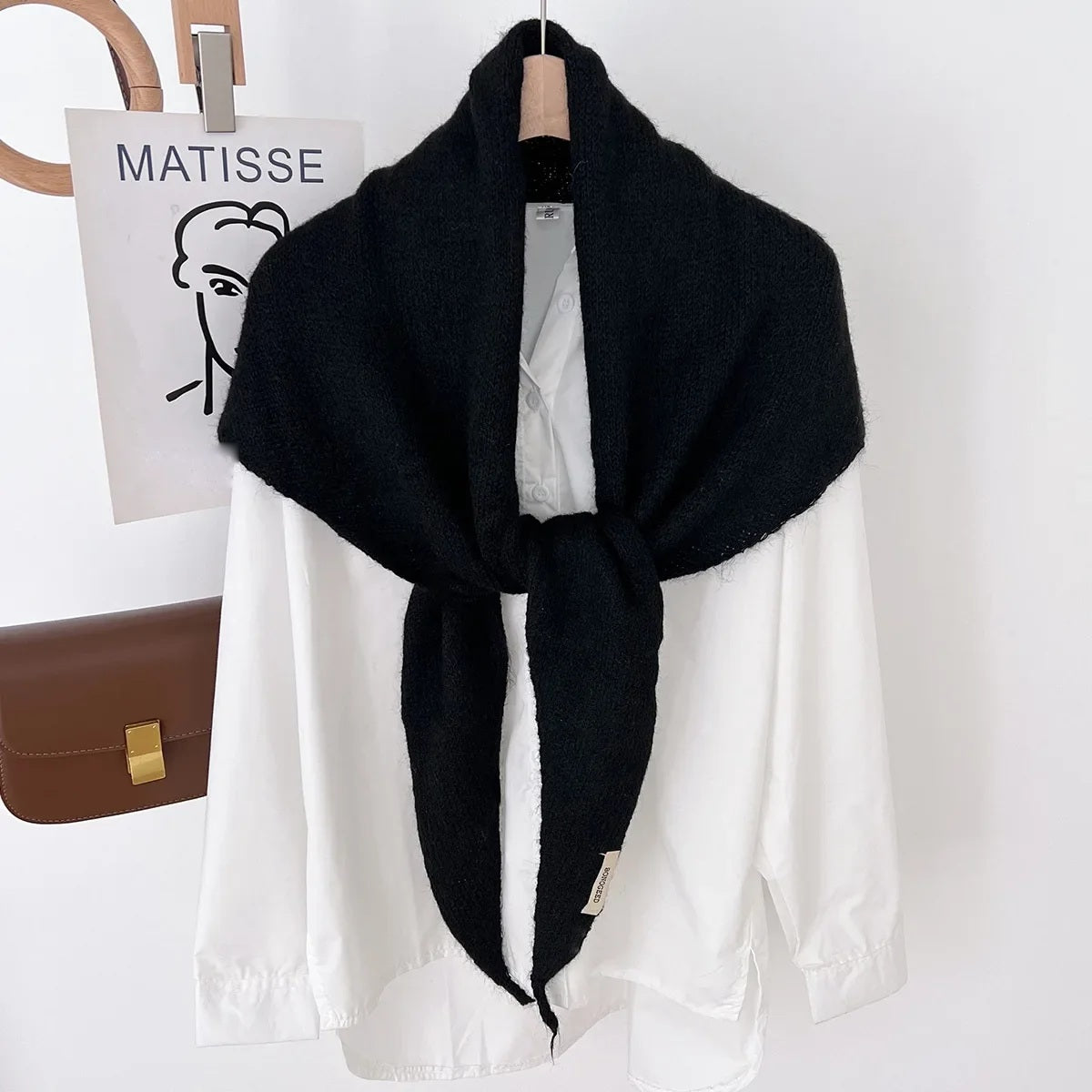 Black knit triangle wool scarf displayed on a hanger
