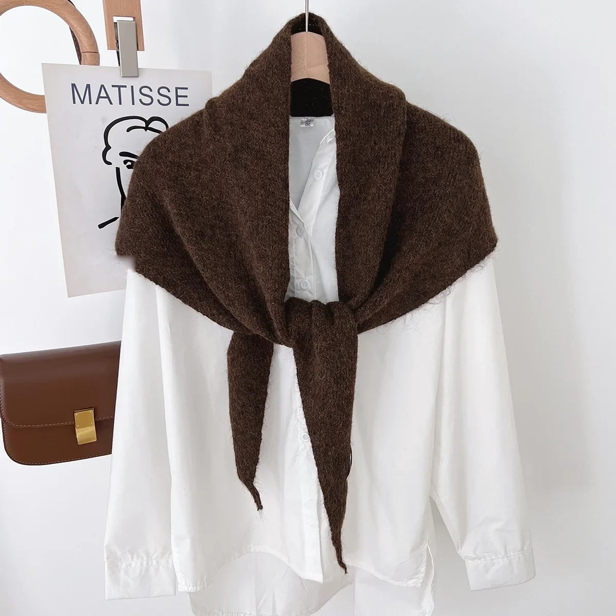 Brown knit triangle wool scarf displayed on a hanger