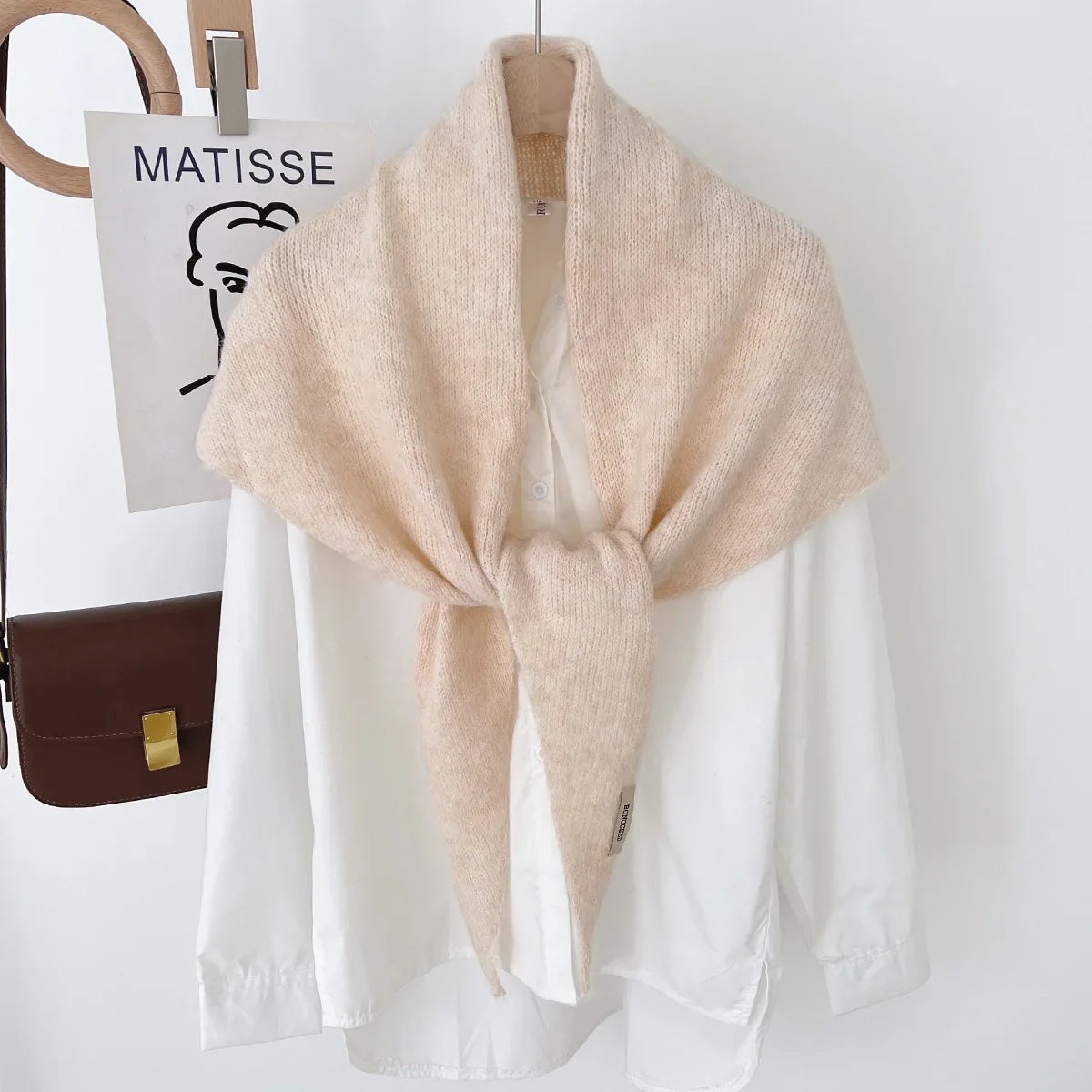 Cream knit triangle wool scarf displayed on a hanger