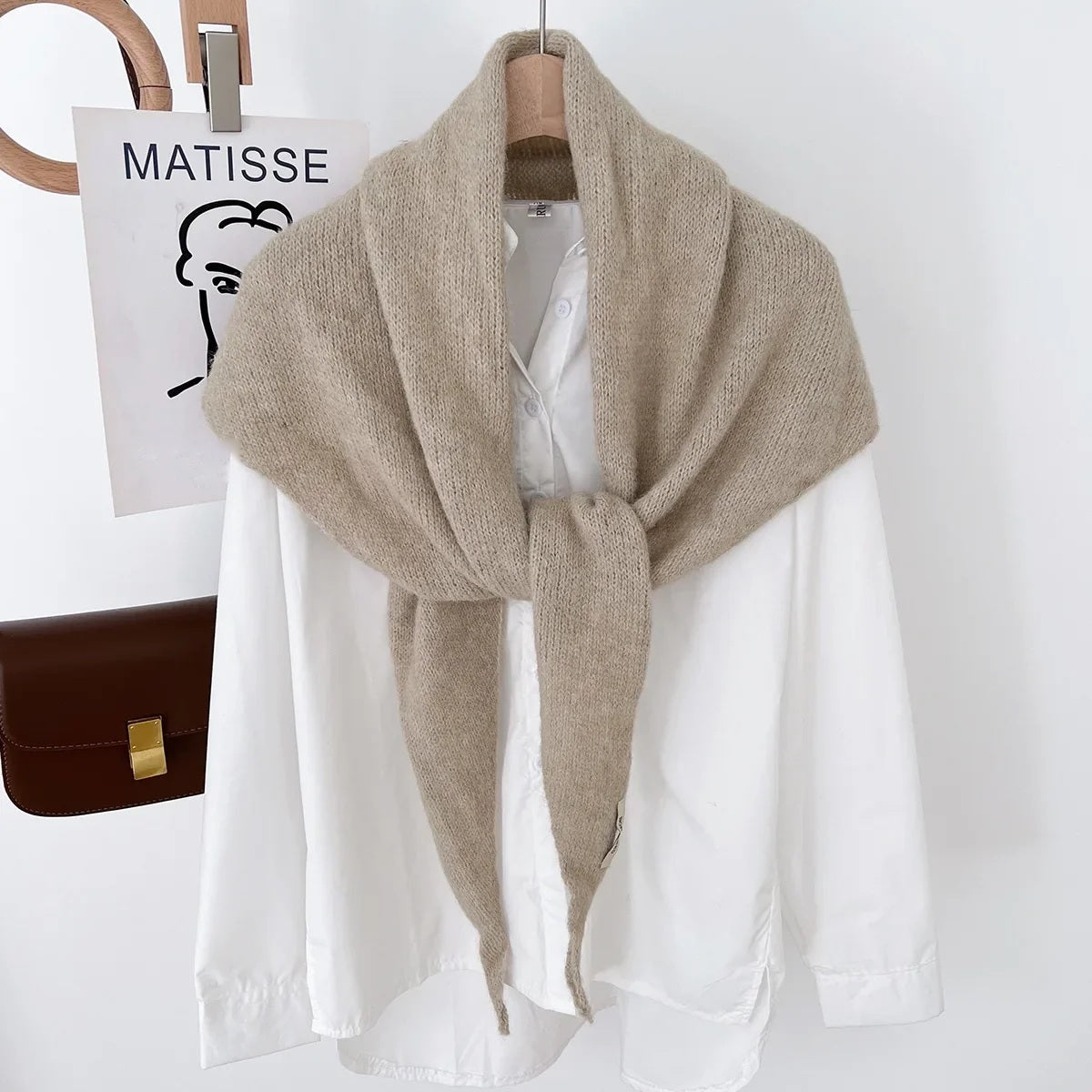 Beige knit triangle wool scarf displayed on a hanger