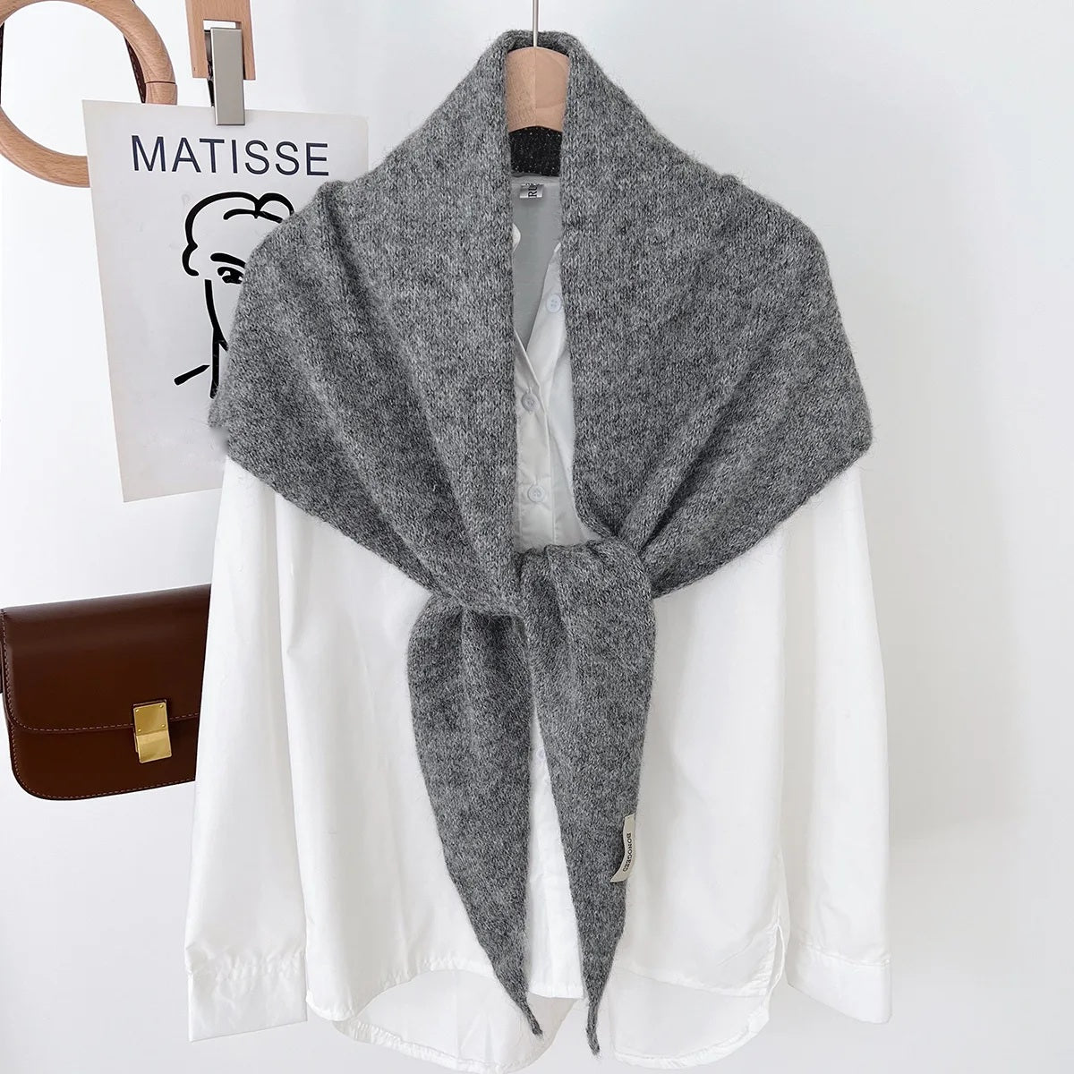 Grey knit triangle wool scarf displayed on a hanger