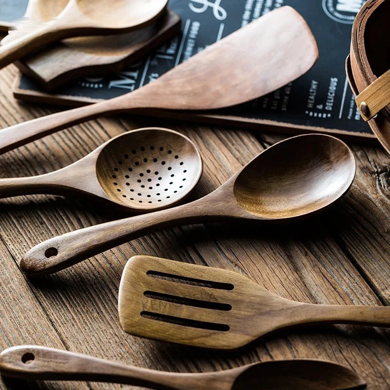 Close up of wooden slotted spoon and spatula on a rustic wooden board