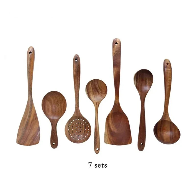 Seven piece wooden cooking utensil set laid out on a white background