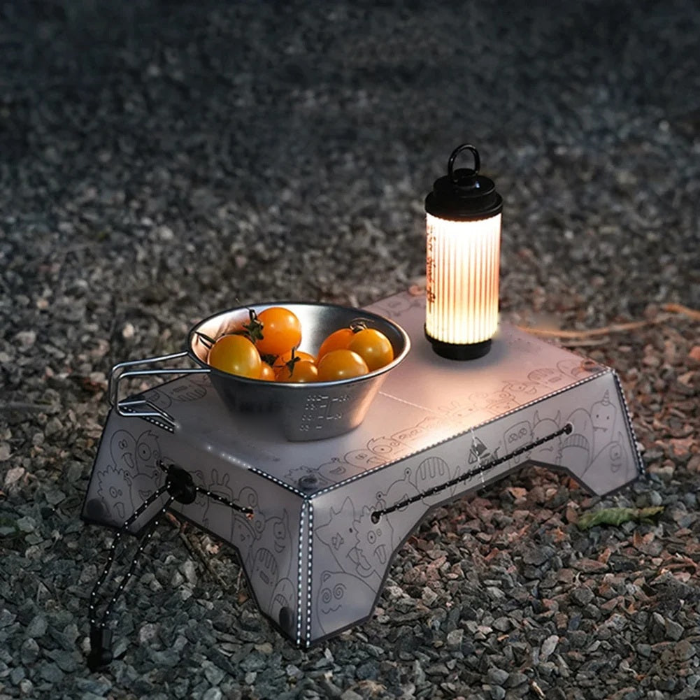Camping table at night holding a bowl of tomatoes and a lantern