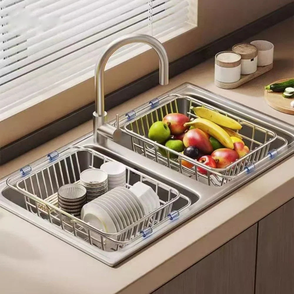 Expandable stainless steel drying rack over a double sink with fruit and dishes