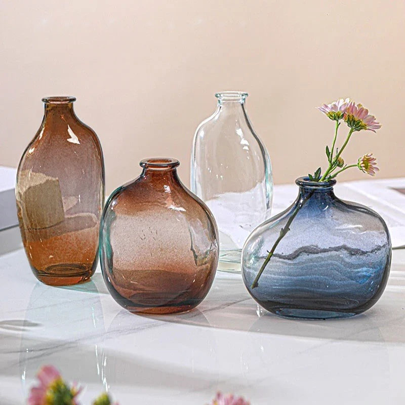 Retro glass bud vases in amber, clear and blue on a white table