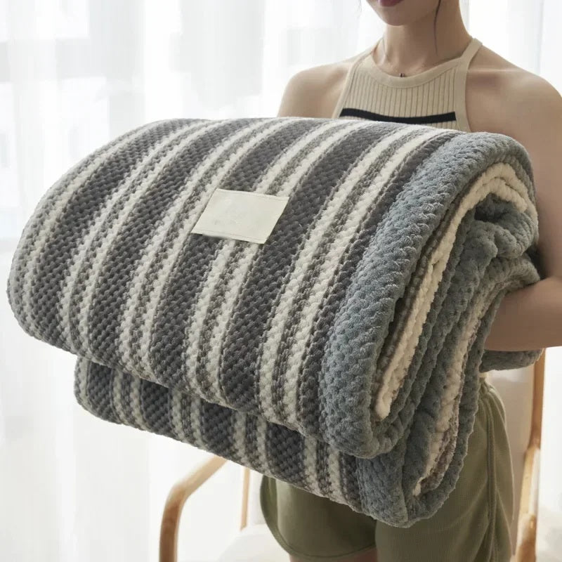 Rolled chenille knit throw blanket held in the arms, grey stripe