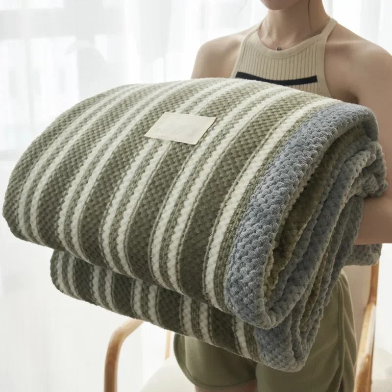 Rolled chenille knit throw blanket held in the arms, olive stripe