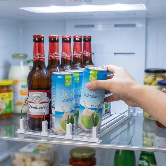 Hand taking a can from the push-style drink dispenser rack in a fridge